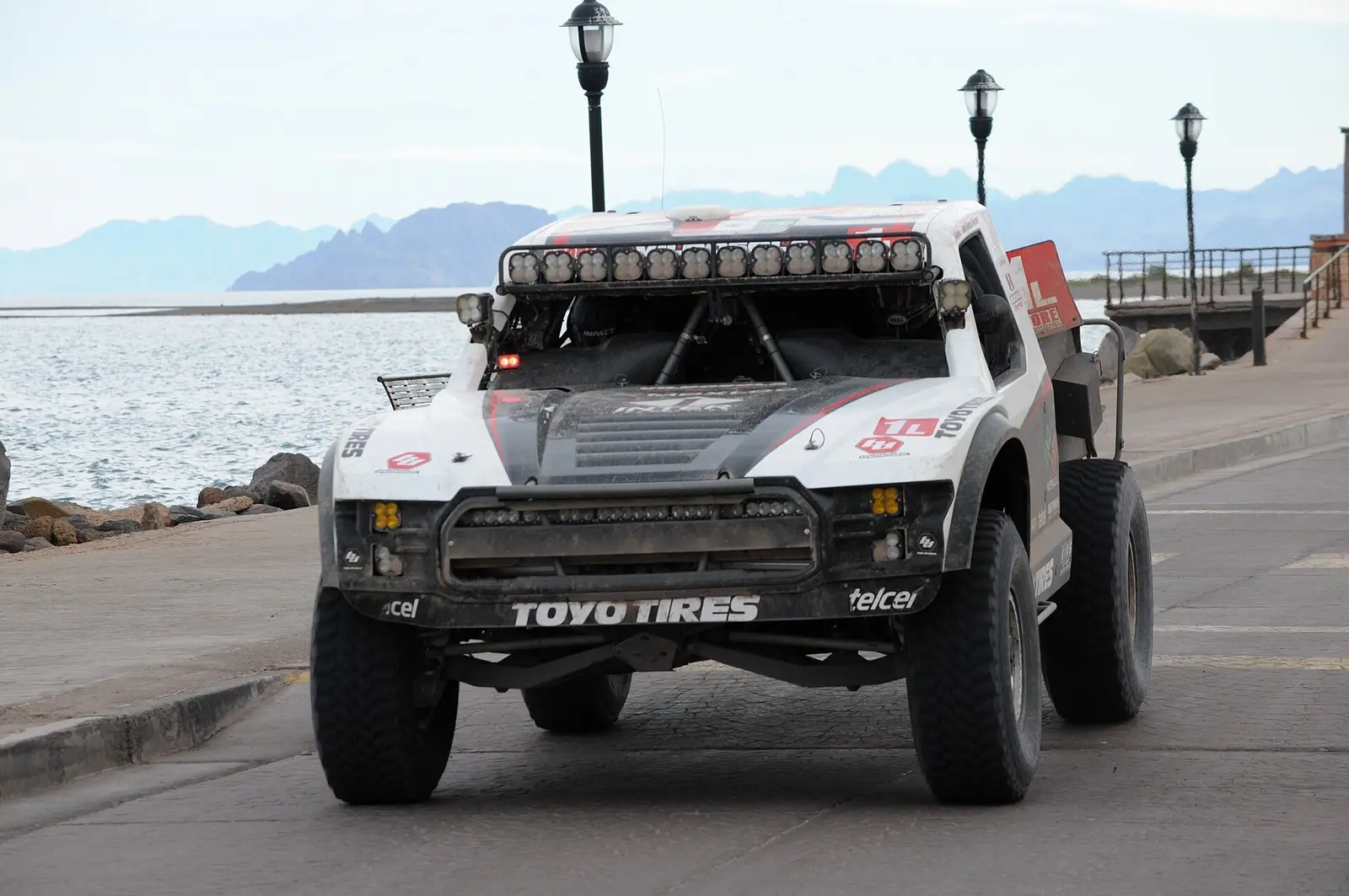 Baja 1000 race truck parked on the waterfront Malecon in Ensenada with mountains behind